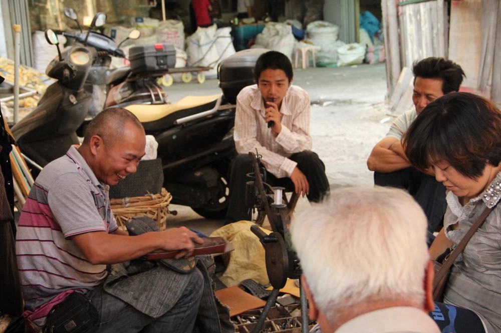 Ji, on the left, mending shoes and talking with customers. (Photo by Winner)