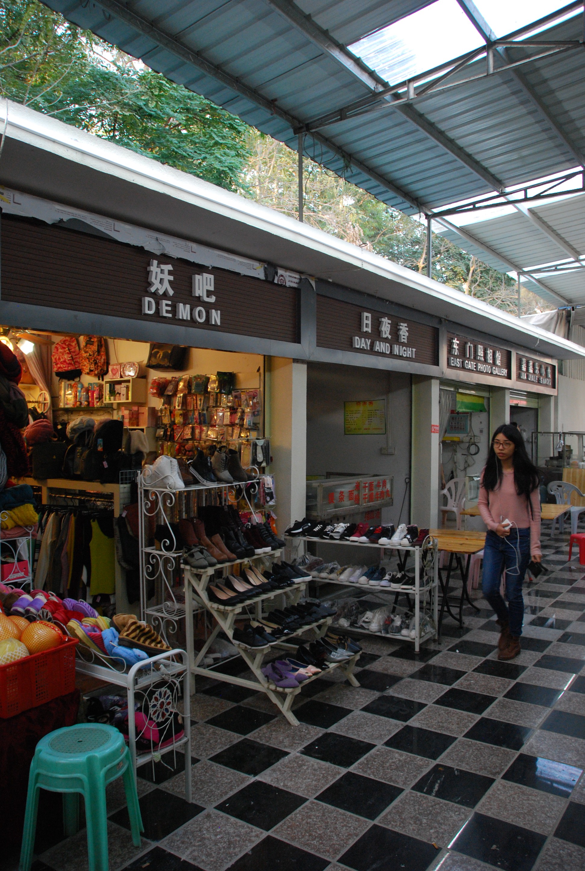 A passerby in the narrow alley of shops at East Gate. Uniform signs and awnings appeared on shops and restaurants over the weekend. Photo: John Noonan