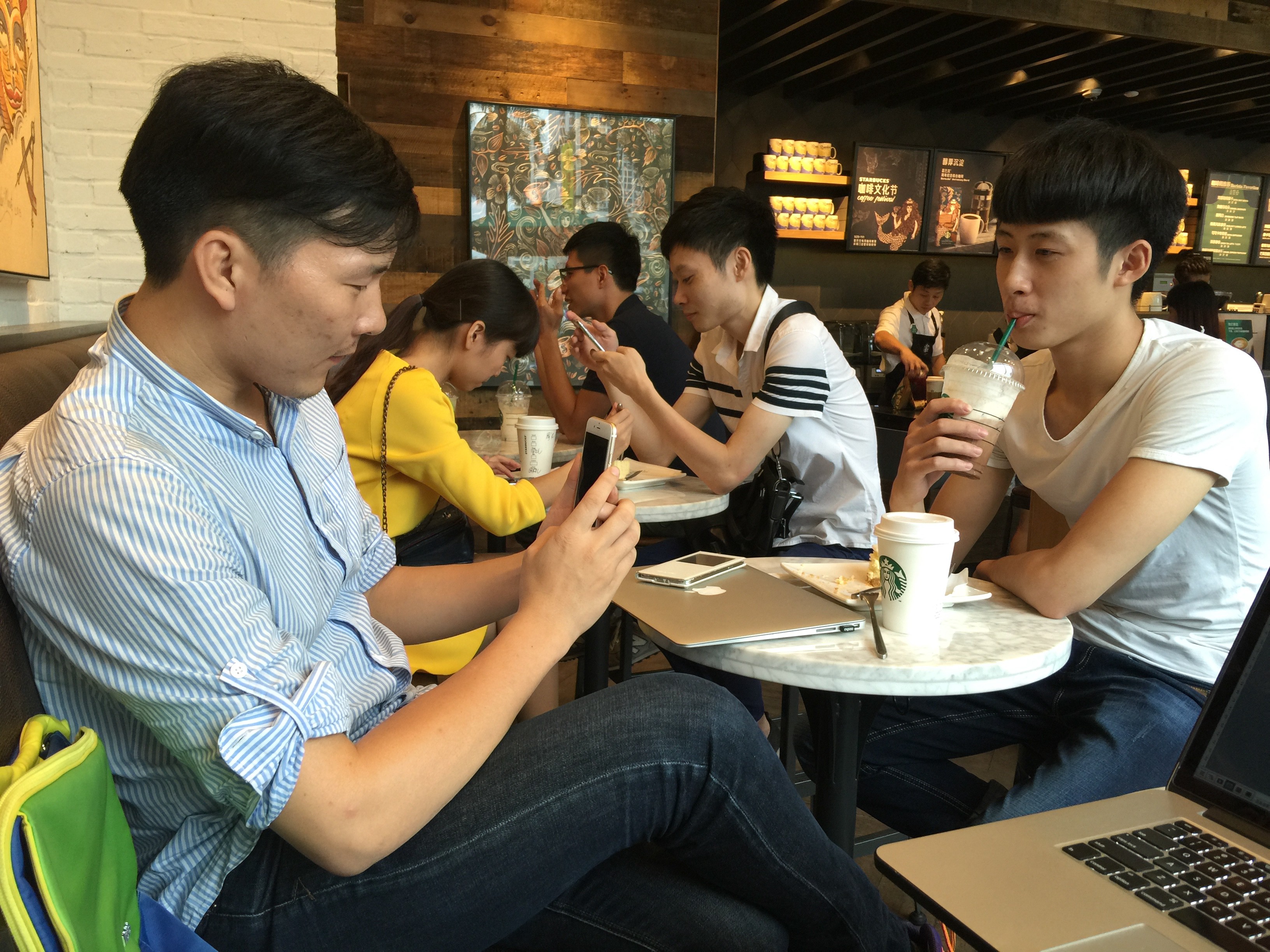 Cai Xiaodong, seated on the left, takes a photo of his friend at Starbucks. Photo: Wency Lin